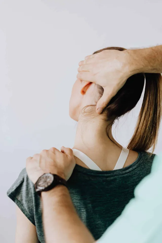 Une personne fait un massage du dos et de la nuque à une femme vue de dos.